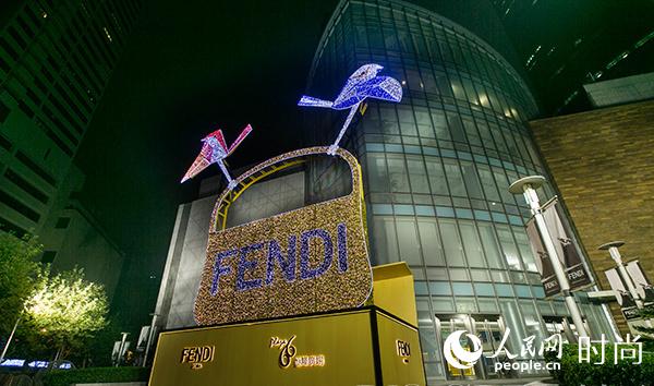 �㳡����һ�ˣ���ֻС�������FENDI��ɫ��ʥ����У�����һ��10�׸ߵ�FENDI����Baguette�ִ�װ�á������ڹ㳡��Baguette���Ž�ɫ�Ľ���ɫ����˸��ҫ�۵Ĺ�â������ӹ��������ϵĽ�ɫ���գ�����鶯�����ŵƹ���������������ϣ������Զ����